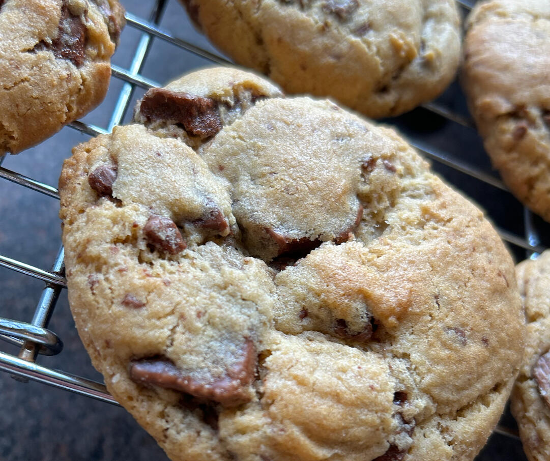 a close up photo of a large chocolate chip cookie showing big chunks of milk chocolate
